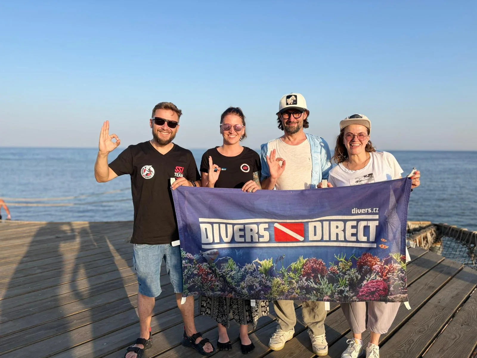 Parta Divers s bannerem na společné výpravě u moře